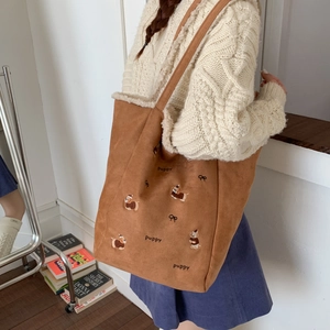 Detail of corduroy shoulder bag with puppy embroidery and warm faux fur lining texture