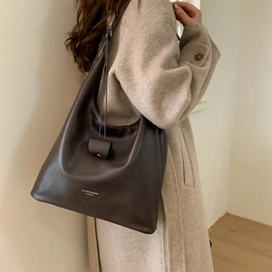 Dettaglio borsa shopper in morbida pelle marrone scuro con logo portata sulla spalla