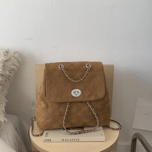 Détail d'un sac à dos vintage en daim marron matelassé avec fermoir rotatif argenté