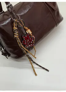 Detail of vintage brown tote bag with glossy leather texture and heart leopard bear charm