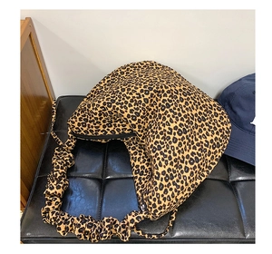 Detail of leopard print shoulder bag featuring ruched strap and half-moon silhouette