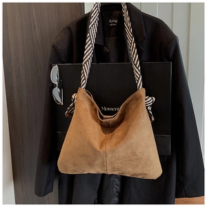 Detail of brown suede Hobo bag featuring striped woven strap and side bow decoration
