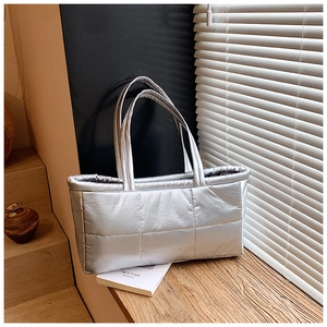 Detail of silver quilted tote bag showing padded metallic fabric and stitching textures