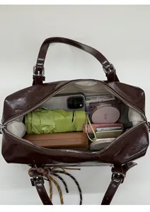 Top view of spacious interior in oil wax leather bag holding phone, umbrella and cosmetics