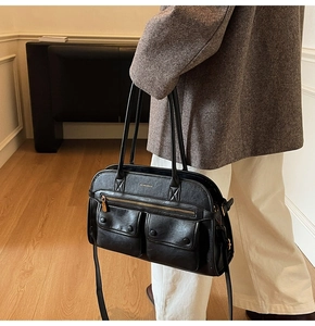 Detail shot of black faux leather tote with two front flap pockets and metallic zipper
