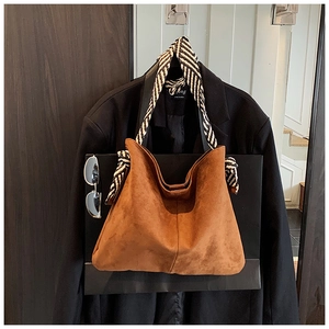 Detail of brown suede hobo bag with black and white striped scarf wrapped on handle