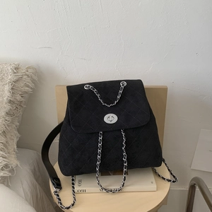 Détail d'un sac à dos vintage en daim matelassé noir avec chaîne et fermoir pivotant argenté