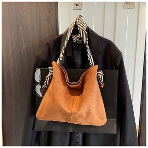 Close-up of caramel suede tote bag with striped woven strap and knot detail