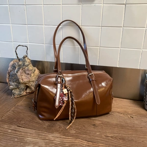 Detail of brown leather Boston bag with leopard heart charm and vintage tassels