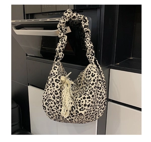 Detail of leopard print hobo bag featuring pleated handles and decorative lace bow charm