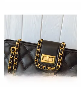 Close-up of black quilted leather shoulder bag with gold chain and metal twist lock
