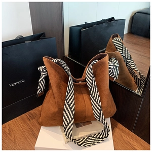 Detail view of large caramel suede tote bag with striped woven strap and magnetic closure