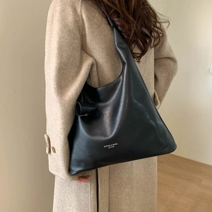 Dettaglio di una borsa hobo in pelle nera con scritte bianche su cappotto invernale