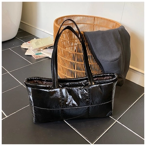 Detailed macro view of the glossy black quilted puffer tote bag with durable padded straps