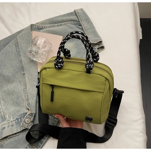 Detail view of avocado green crossbody bag with woven handles and water-resistant nylon fabric