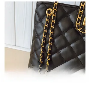 Detailed close-up of black quilted leather shoulder bag with golden chain strap