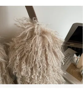 Detail of plush camel bucket bag with curly faux fur texture and brown leather strap