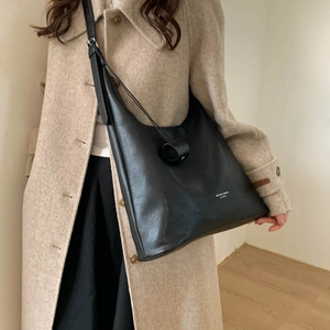 Dettaglio della borsa hobo in pelle martellata nera con tracolla larga e logo inciso