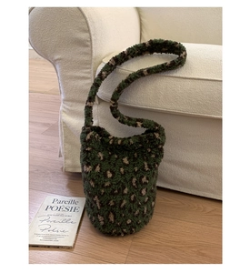 Detail of green leopard print plush bucket bag leaning on a soft fabric sofa