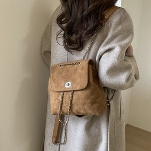 Détail d'un sac à dos vintage en daim marron avec matelassage porté par un mannequin