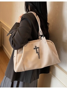 Beige pebbled leather tote bag with vintage metal cross pendant and chain detail