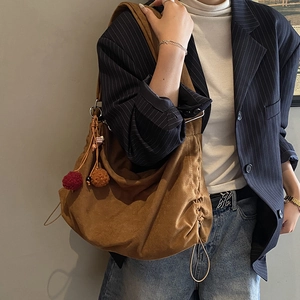 Brown suede slouchy tote bag with colorful pompom charm shown on a model outfit