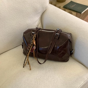 Detail of dark brown glossy leather handbag with silver zipper and colorful tassel charm