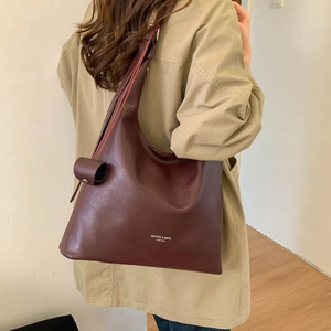 Dettaglio della borsa tote in pelle marrone scuro con logo Muting & Bags e ciondolo