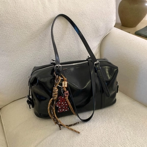 Detail of minimalist black patent handbag with leopard bear and fringe accessories