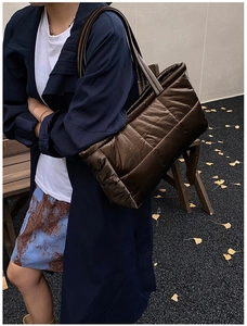 Detail of dark brown quilted puffer tote bag with long shoulder strap in autumn setting