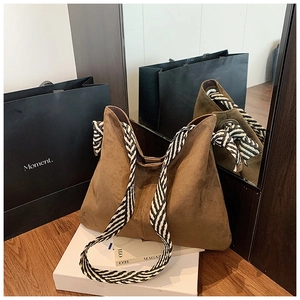 Detail of earthy tote bag with chic black and white striped woven wide shoulder strap
