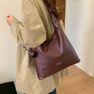 Dettaglio borsa tote in pelle opaca rosso vino con ciondolo cilindrico elegante