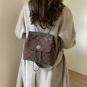 Détail du sac à dos en daim matelassé marron avec fermoir rotatif et bandoulière chaîne