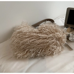 Detail of plush faux fur shoulder bag with leather strap and dense curly texture