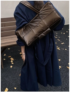 Outdoor shot of a large quilted down tote bag in metallic bronze with fluffy texture