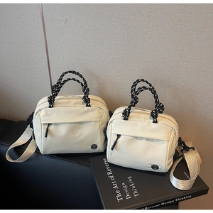 Detail of cream nylon crossbody bag featuring woven handles and wide shoulder strap