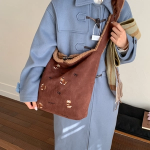 Detail of corduroy shoulder bag featuring puppy embroidery and warm faux shearling trim