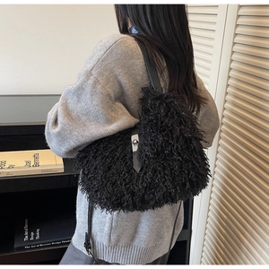Detail of black faux fur shoulder bag with leather strap and metal clasp on model