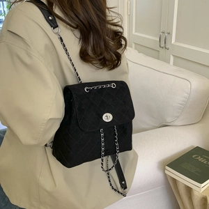 Détail du sac à dos en daim noir matelassé avec fermoir rotatif et chaîne argentée