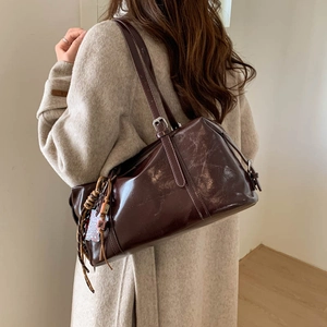 Detail of dark brown glossy underarm bag with silver buckle and vintage tassel charm