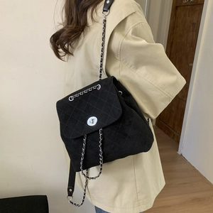 Détail d'un sac à dos vintage en daim avec motif matelassé et bandoulière en chaîne
