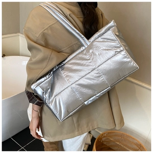 Close-up of silver quilted puffer tote bag with metallic finish and wide shoulder straps