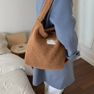 Brown corduroy tote bag with SEEYOU label worn over a blue coat in a cozy home setting