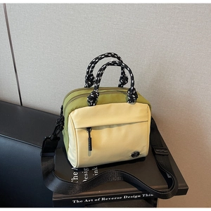 Detail of green and beige nylon crossbody bag with rope handles on black books