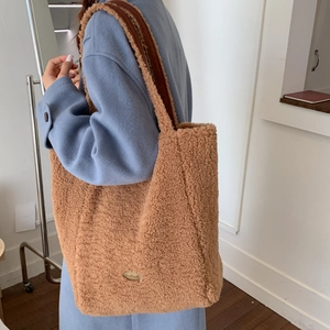 Close-up of brown faux shearling tote bag with a golden handmade metal plate detail