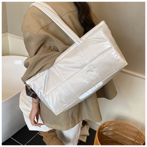 Detailed side view of the quilted white down tote bag with a glossy nylon texture finish
