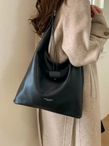 Grande borsa tote minimalista in pelle nera indossata da una modella, stile vintage