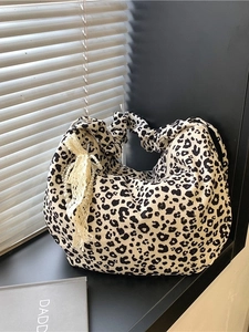 Leopard print hobo bag with ruched shoulder strap and pearl bow charm on a window sill