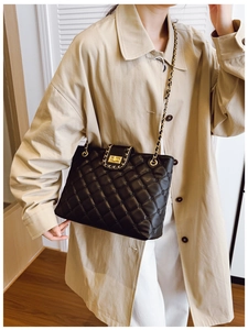 Détail de la texture en cuir noir matelassé avec bandoulière chaîne dorée du sac à main