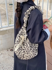 Leopard print pleated tote bag with pearl bow pendant detail shown on shoulder
